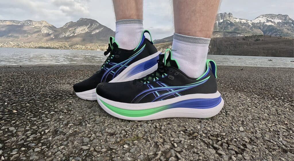 Black ASICS GEL sneakers worn outdoors with blue and green details