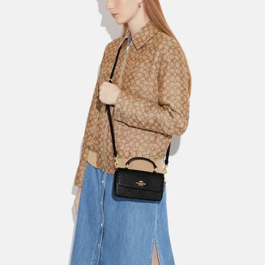Woman carrying a black Coach structured crossbody bag