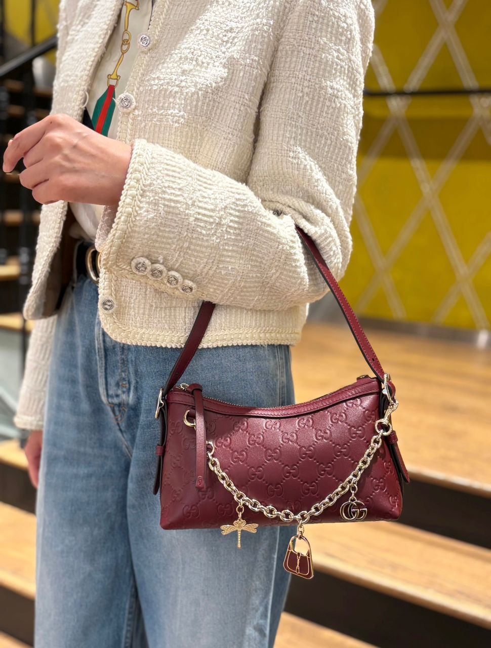Woman carrying a burgundy Gucci compact crossbody bag