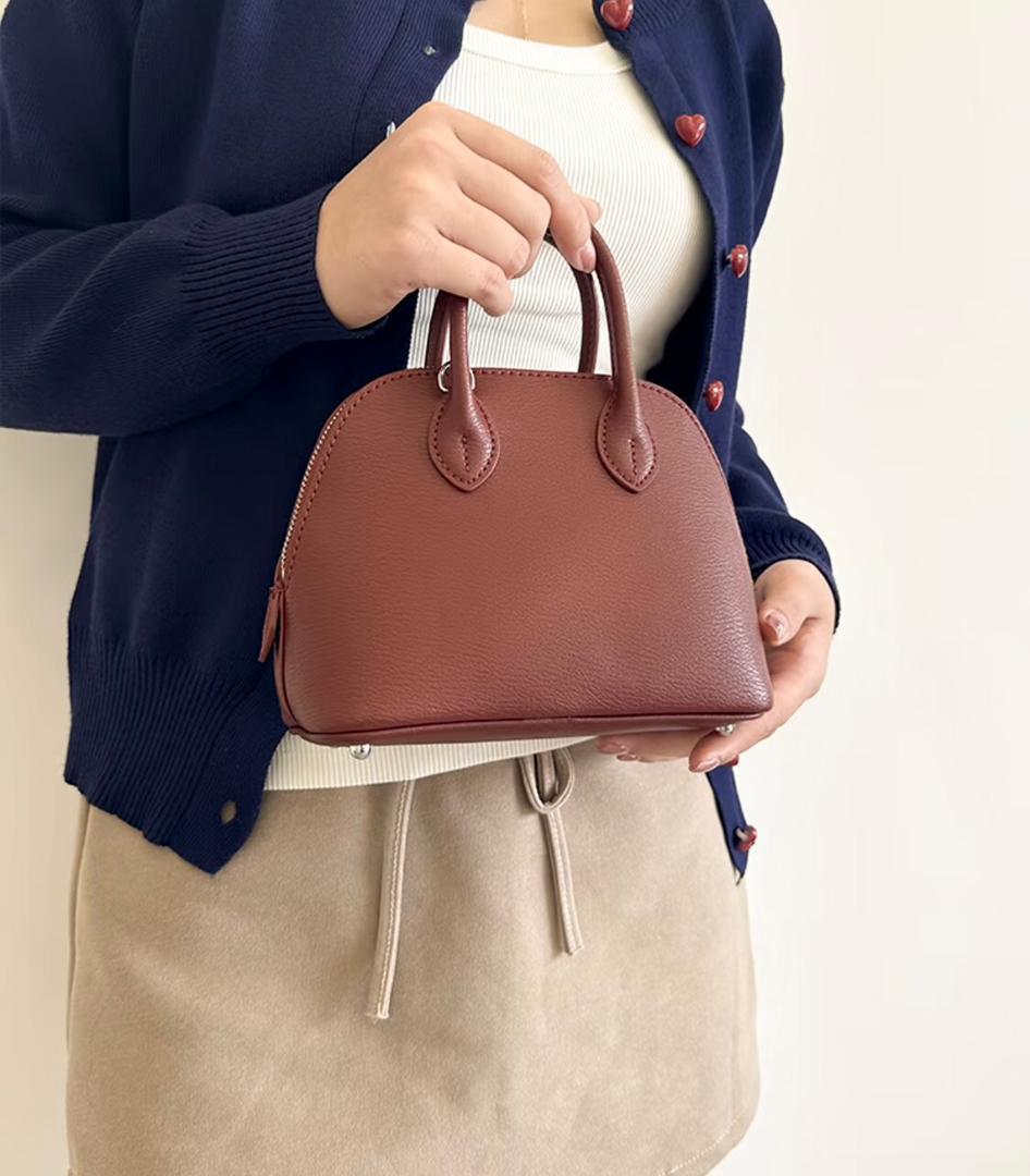 Woman styling a taupe Hermès mini handbag