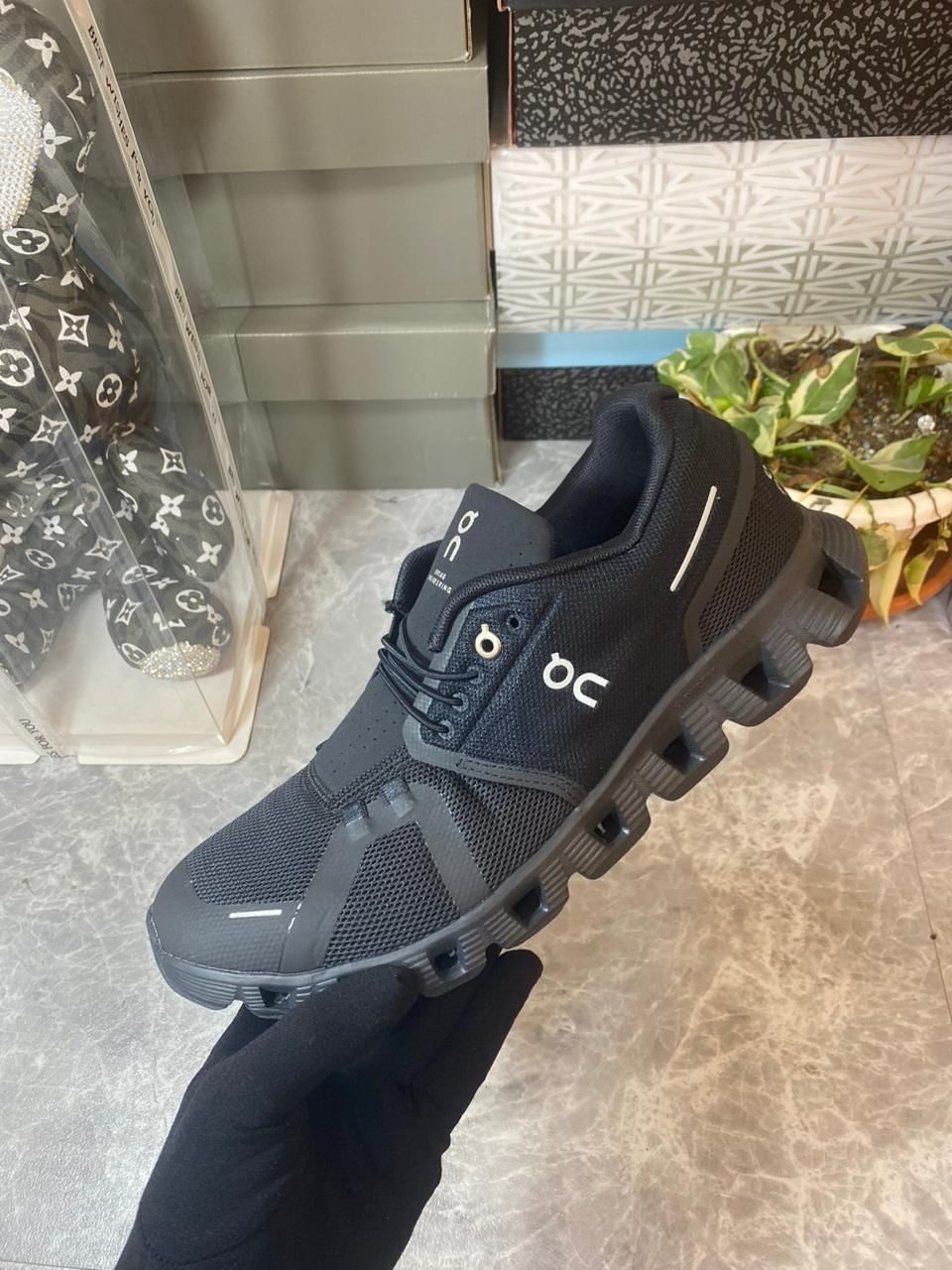 On Cloudventure Waterproof men’s black trail shoe held in hand