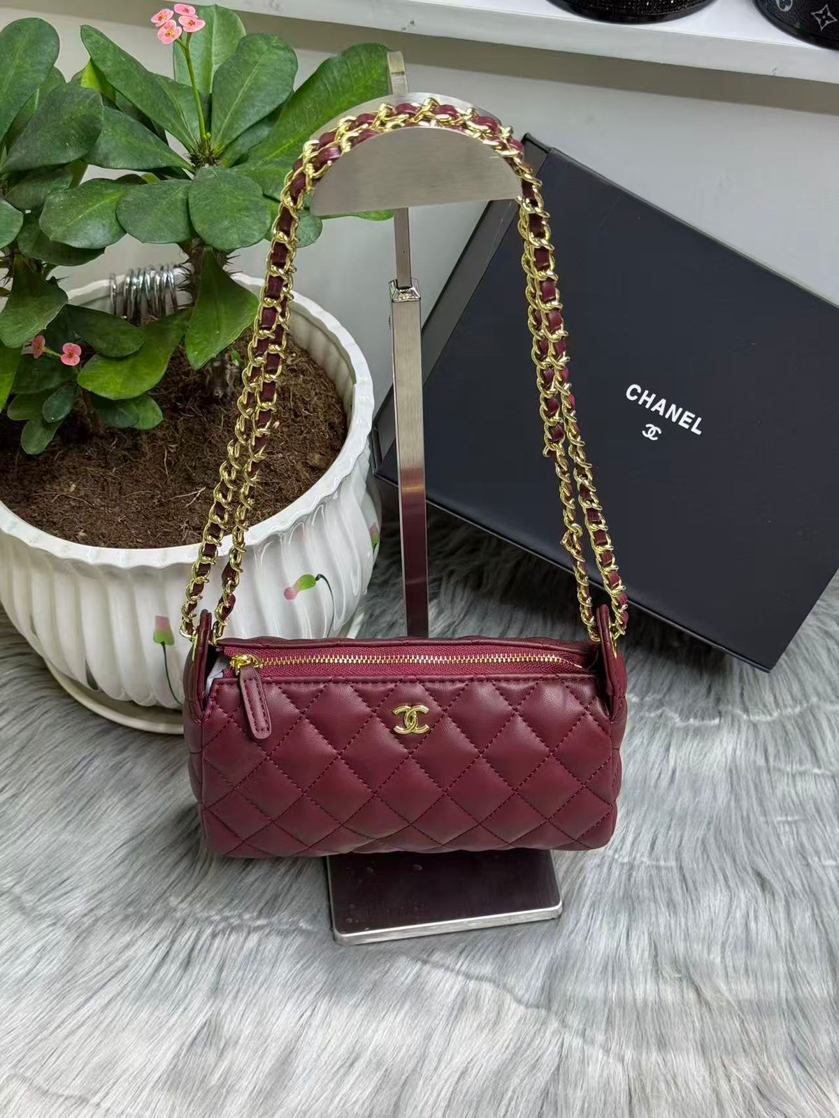 Burgundy red quilted leather mini chain bag on display stand